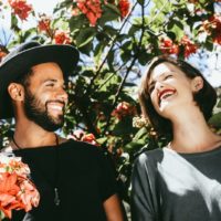 man and woman laughing while standing near tree